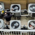 Overhead shot of HVAC tech servicing ACs for electrical service upgrade